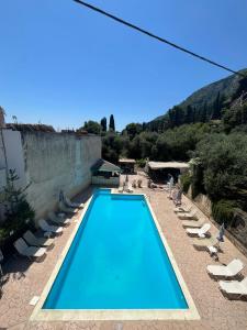 a blue swimming pool with lounge chairs and a mountain at Avgoustina Venus Studios in Benitses