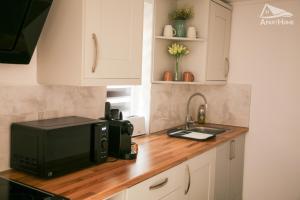 a kitchen counter with a microwave and a sink at ApartHome in Makó