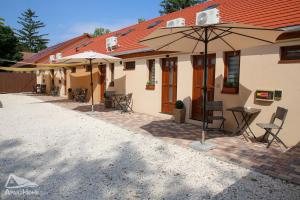 a building with tables and umbrellas in front of it at ApartHome in Makó