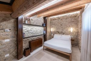 a bedroom with a bed and a stone wall at Borgo Baccile by Vini Fantini in Crecchio +129 photos