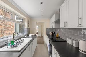a kitchen with white cabinets and black counter tops at Park Crescent - Quaint Victorian Home With Free Parking in York +53 photos