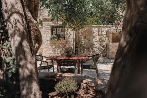 a table and chairs in a yard with a stone wall at Guince House by All About Paxos in Oziás