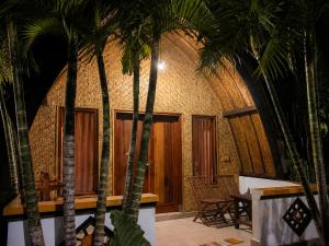a group of palm trees in a room with tables at Warna Cottage in Gili Trawangan