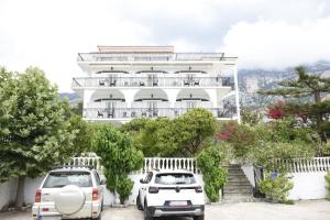 two cars parked in front of a white building at Venus Studios in Vlachata