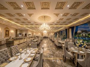 a dining room with tables and chairs and a chandelier at Regency Suite Hotel in Lahore