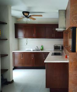 a kitchen with wooden cabinets and a ceiling fan at Top Pool Condo in Ixtapa's Hotel Area in Ixtapa