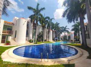 a swimming pool in front of a building with palm trees at Top Pool Condo in Ixtapa's Hotel Area in Ixtapa
