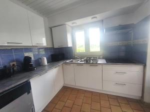 a kitchen with white cabinets and a sink and a window at Sisters home in Marcinelle
