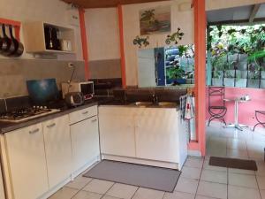 a kitchen with white cabinets and an open door at La Case du Pêcheur in La Trinité