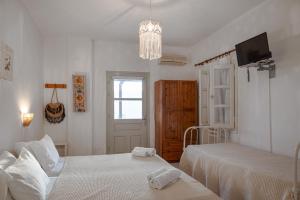 a white bedroom with two beds and a chandelier at Marietta Studios Patmos in Skala +31 photos