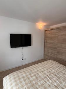 a bedroom with a bed and a flat screen tv on the wall at Greta Apartment in Alytus