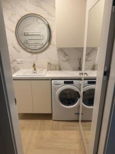 a bathroom with a washing machine and a mirror at Greta Apartment in Alytus +40 photos