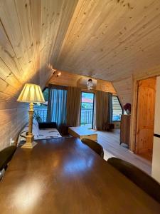 a room with a large wooden table with a lamp at Chalet Marta in Kobuleti