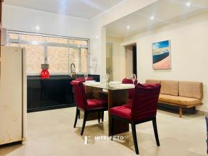 a kitchen and dining room with a table and red chairs at Casa Central Px Matriz c/ Churrasqueira, 2 Suítes in Poços de Caldas