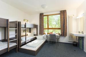 アーヘンにあるユーゲントヘアベルゲ アーヘンの二段ベッド、テーブル、シンクが備わる客室です。