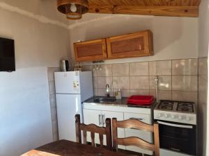 a kitchen with a stove and a white refrigerator at Cabaña de Mia in Villa Traful