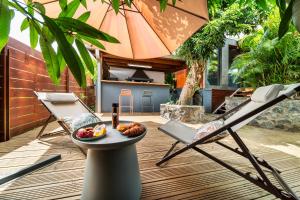 a patio with two chairs and a plate of food on a table at Le Secret Tropical - Parenthèse jacuzzi in Sainte-Marie