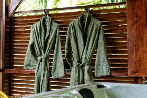 a robe hanging on a wooden wall next to a sink at Le Secret Tropical - Parenthèse jacuzzi in Sainte-Marie