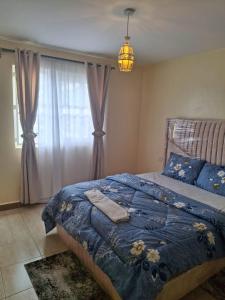 a bedroom with a bed with a blue blanket and a window at Liaden 2 Bedroom Apartment in Nairobi