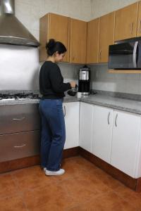 a woman standing in a kitchen preparing food at Hospedaje la gran Tenochtitlán in San Martín Hidalgo