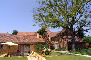 a man sitting under an umbrella in front of a house at La Cense De La Mérelie - Le Logis in Saint-Geniès