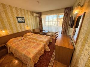 ein Hotelzimmer mit zwei Betten und einem Schreibtisch in der Unterkunft Hotel Olymp in Sonnenstrand + 11 Fotos
