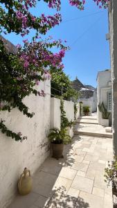 a courtyard with flowers on a white wall at Montesanto 60 Suite & Relax Alberobello in Alberobello