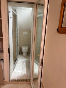 a glass door leading to a bathroom with a toilet at SnowWhite Home in Porto Ercole +3 photos