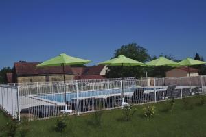 a fence with chairs and umbrellas next to a pool at La Cense De La Mérelie - Le Logis in Saint-Geniès