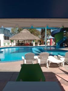 a pool with white chairs and a green table at Hotel York in Guamúchil