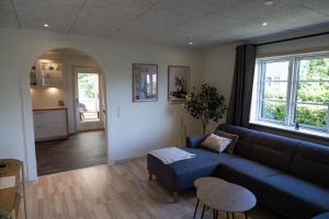 a living room with a blue couch and a kitchen at Billund Guest Lodge 2 in Hejnsvig