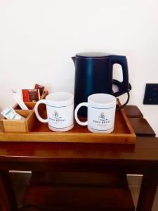 three coffee mugs are sitting on a wooden tray at Port Royal Residence in Trincomalee