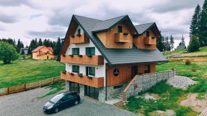 a house with a car parked in front of it at Marisel Escape Chalet in Mărişel