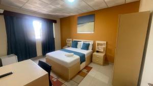 a hotel room with a bed and a desk and a table at Residencial FSFA in Praia