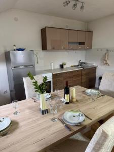a kitchen with a wooden table with plates and wine glasses at Airport Studio apartman ravna gora in Mitrovići