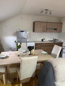 a kitchen with a wooden table and chairs in a kitchen at Airport Studio apartman ravna gora in Mitrovići +5 photos