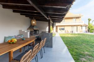 a patio with a wooden table and chairs and a grill at Aeliah in Anavyssos