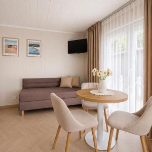 a living room with a couch and a table and chairs at Szarotka Łeba - nowe domki blisko plaży in Łeba