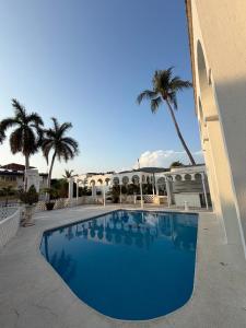 a blue swimming pool in front of a building with palm trees at Casa Arabesca in Acapulco