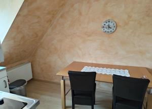 a dining room table with two chairs and a clock on the wall at Fewo Steuerboard in Röbel