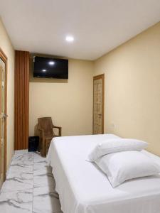 a bedroom with a white bed and a television on the wall at Hotel Castillo in San Pedro Sula +2 photos
