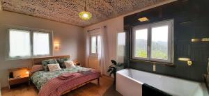 a bedroom with a bed and a bath tub and windows at La petite maison d'Hose in Monistrol-sur-Loire