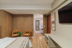 a hotel room with a bed and a flat screen tv at Havana Palace Hotel II Uberaba in Uberaba