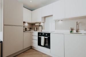 a white kitchen with white cabinets and appliances at Saturn Studio by Navie Stays in Poole