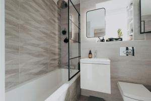 a bathroom with a sink and a tub and a toilet at Saturn Studio by Navie Stays in Poole +16 photos