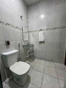 a white bathroom with a toilet and a sink at Executivo Central 102 in Ipatinga