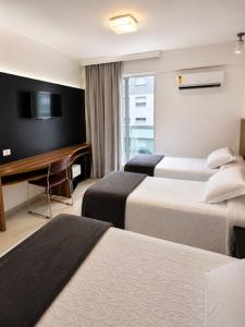 a hotel room with three beds and a desk and a television at Atlântico Golden Apart Hotel in Santos +18 photos