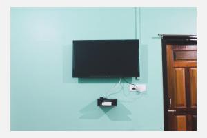 a flat screen tv hanging on a blue wall at Mini Emphum 2BHK Apartment in Namsai