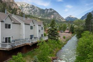 a river with houses and mountains in the background at River Park 1244 in Ouray