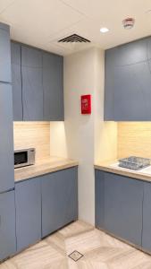 a kitchen with blue cabinets and a microwave at برج داماك الرياض in Riyadh